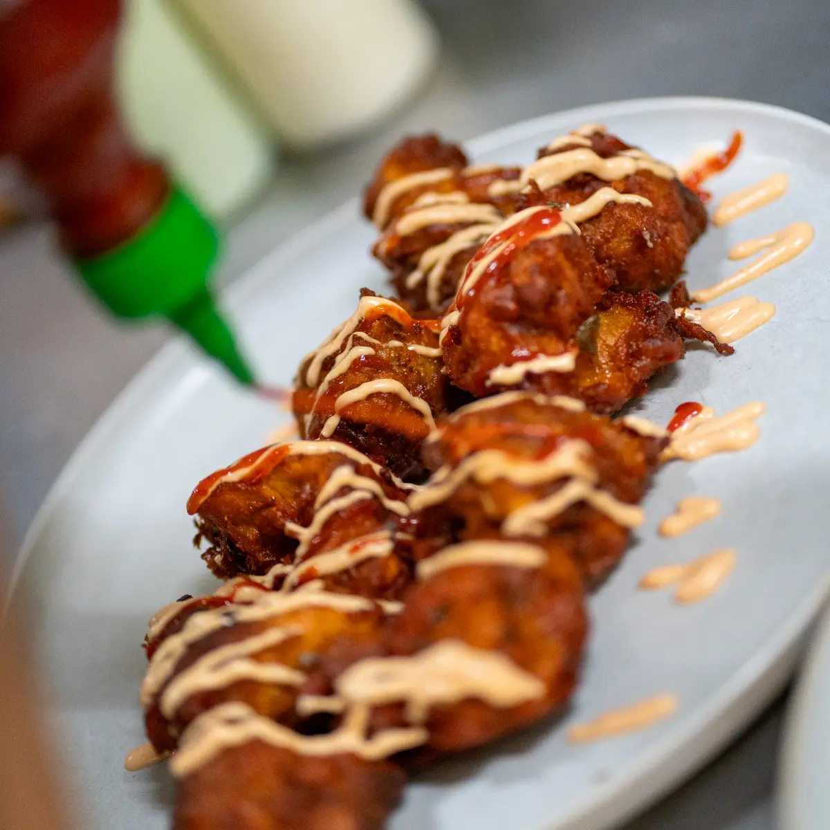 Server pouring hot sauce on food.