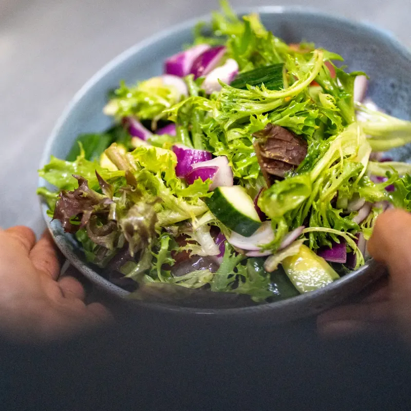 Server taking salad from kitchen counter.